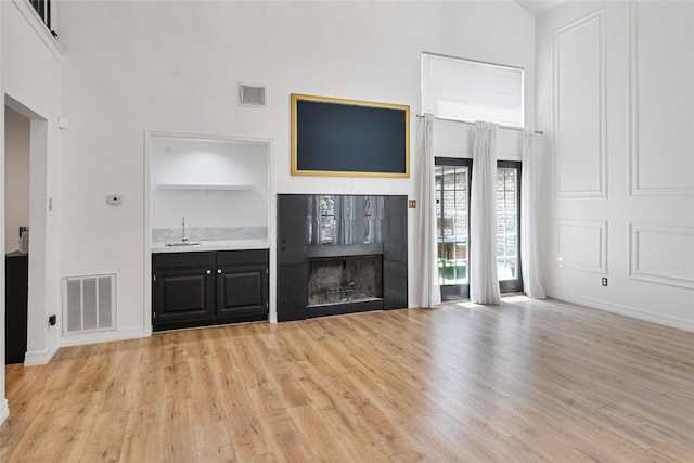 8033 Oakwood Forest Dr, Houston, TX 77040 - unfurnished living room with a towering ceiling, light wood-style flooring, and a tile fireplace