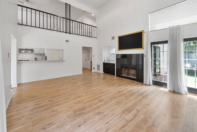 8033 Oakwood Forest Dr, Houston, TX 77040 - unfurnished living room with a towering ceiling, a fireplace, and light wood-style floors