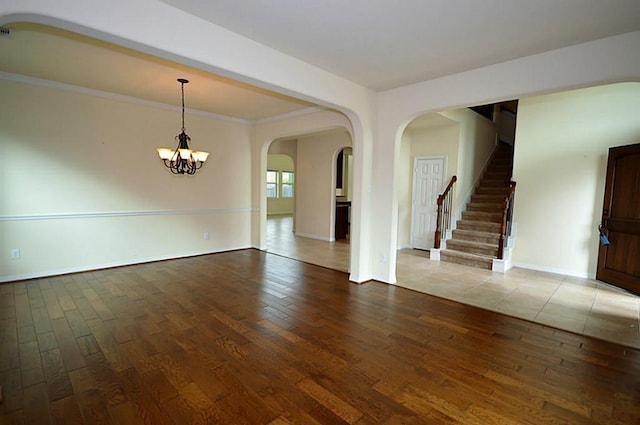 4202 Misty Waters Ln, Katy, TX 77494 - unfurnished room featuring hardwood / wood-style flooring, arched walkways, a chandelier, stairs, and crown molding