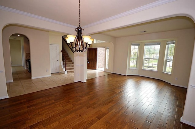 4202 Misty Waters Ln, Katy, TX 77494 - spare room featuring light wood-style floors, a chandelier, arched walkways, stairway, and crown molding