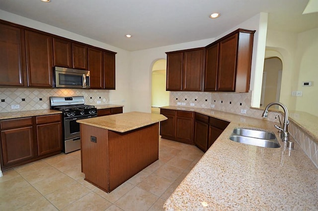 4202 Misty Waters Ln, Katy, TX 77494 - kitchen with stainless steel appliances, arched walkways, light stone counters, a center island, and decorative backsplash