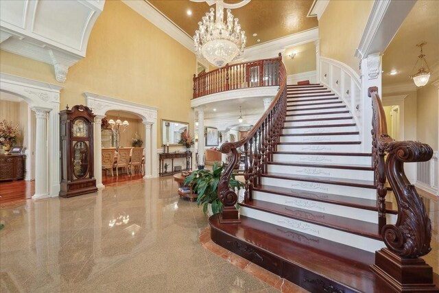 7510 Shadow Creek Dr, Beaumont, TX 77707 - stairs with decorative columns, crown molding, a high ceiling, a chandelier, and granite tiled floors