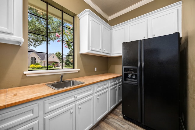 13722 Vinery Ln, Cypress, TX 77429 - kitchen with black refrigerator with ice dispenser, butcher block countertops, crown molding, white cabinetry, and wood finished floors