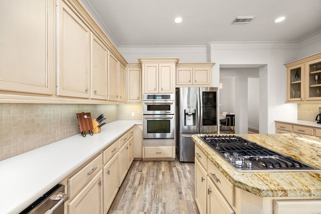 13722 Vinery Ln, Cypress, TX 77429 - kitchen with appliances with stainless steel finishes, cream cabinetry, light wood-type flooring, backsplash, and glass insert cabinets