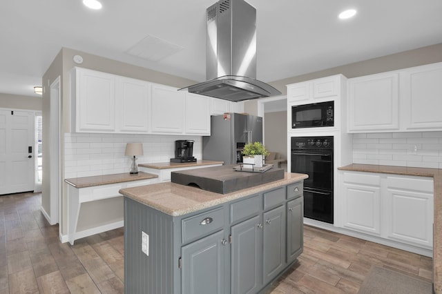 17214 Shadow Valley Dr, Spring, TX 77379 - kitchen featuring island exhaust hood, black appliances, white cabinets, and recessed lighting
