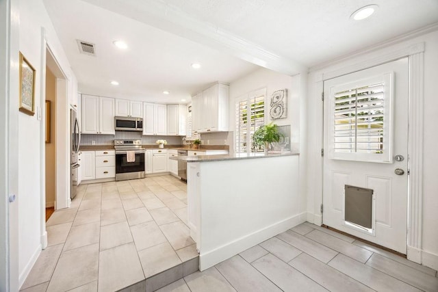 2031 Cheshire Ln, Houston, TX 77018 - kitchen with appliances with stainless steel finishes, white cabinetry, a peninsula, recessed lighting, and crown molding