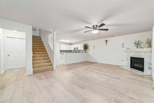 3530 Barkers Crossing Ave, Houston, TX 77084 - unfurnished living room with a ceiling fan, light wood-style floors, stairway, and a premium fireplace