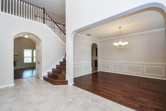 5506 Plumero Meadow Dr, Katy, TX 77494 - tiled foyer entrance featuring arched walkways, crown molding, a chandelier, stairway, and a fireplace