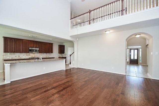 5506 Plumero Meadow Dr, Katy, TX 77494 - unfurnished living room with arched walkways, a high ceiling, and dark wood-type flooring