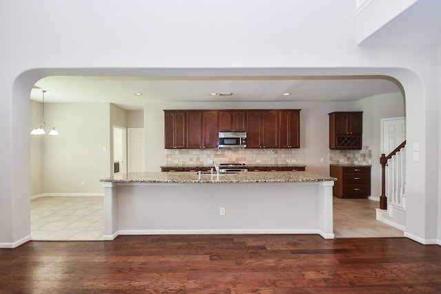 5506 Plumero Meadow Dr, Katy, TX 77494 - kitchen featuring light stone counters, stainless steel microwave, backsplash, light wood-type flooring, and recessed lighting