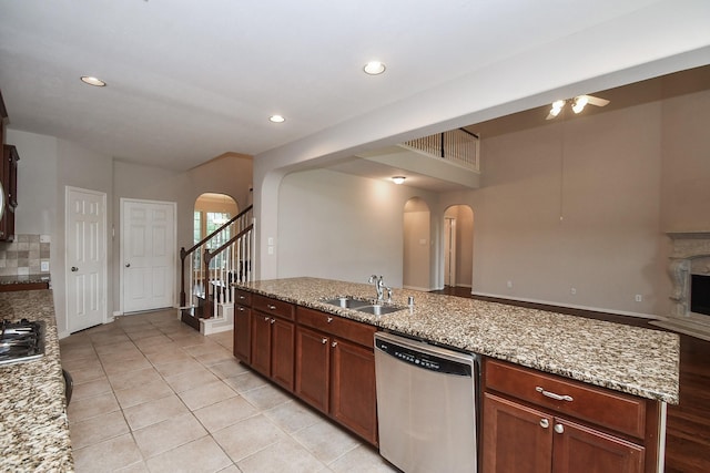 5506 Plumero Meadow Dr, Katy, TX 77494 - kitchen with stainless steel appliances, arched walkways, a fireplace, a ceiling fan, and light tile patterned flooring