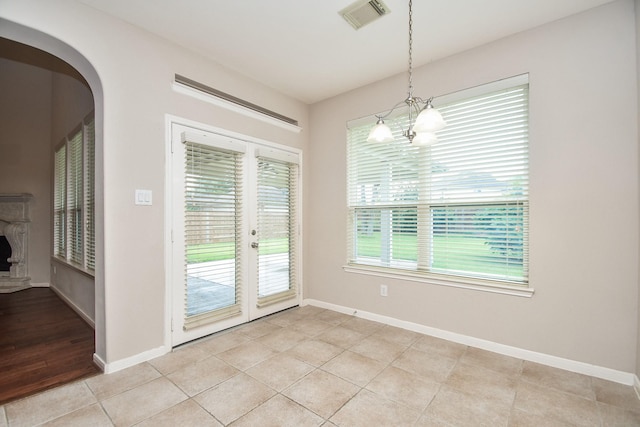 5506 Plumero Meadow Dr, Katy, TX 77494 - unfurnished dining area featuring arched walkways, a chandelier, a fireplace with raised hearth, and light tile patterned floors