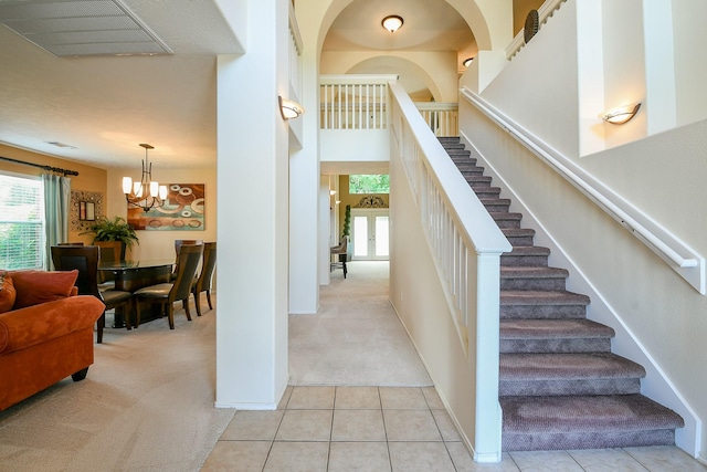 18303 June Forest Dr, Humble, TX 77346 - staircase featuring carpet floors, a chandelier, tile patterned flooring, and a towering ceiling