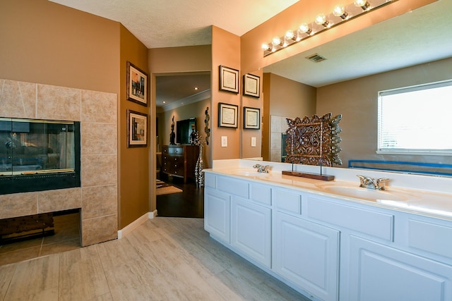 18303 June Forest Dr, Humble, TX 77346 - full bathroom featuring a tiled fireplace, double vanity, and wood finished floors