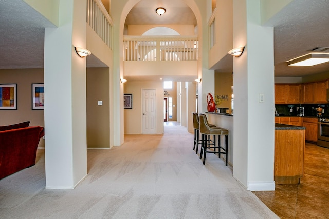 18303 June Forest Dr, Humble, TX 77346 - kitchen with stainless steel stove, dark countertops, brown cabinetry, a textured ceiling, and light colored carpet