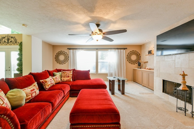 18303 June Forest Dr, Humble, TX 77346 - living room with light carpet, ceiling fan, a fireplace, a textured ceiling, and french doors