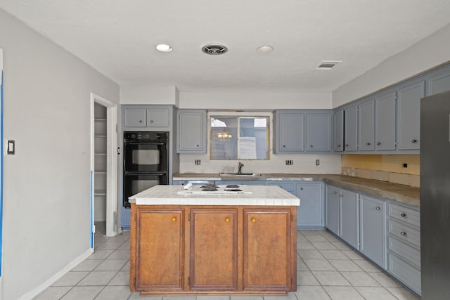 10803 Shawnbrook Dr, Houston, TX 77071 - kitchen featuring a center island, tile counters, light tile patterned floors, white stovetop, and gray cabinetry