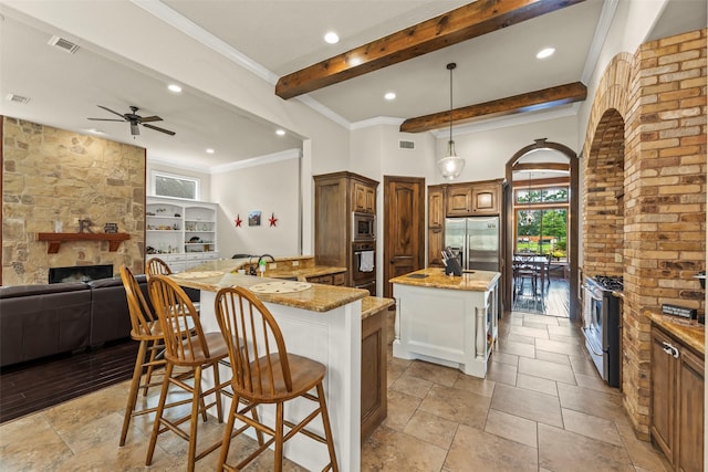 27514 Siandra Creek Ln, Spring, TX 77386 - kitchen with a large fireplace, appliances with stainless steel finishes, open floor plan, beamed ceiling, and healthy amount of natural light