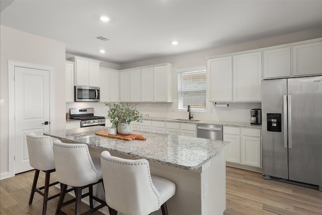 13709 Gaff Rig Dr, Texas City, TX 77510 - kitchen with appliances with stainless steel finishes, light wood-type flooring, a breakfast bar area, a center island, and recessed lighting