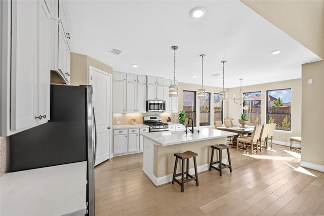 21726 Grayson Highlands Way, Porter, TX 77365 - kitchen with stainless steel appliances, a breakfast bar area, light wood finished floors, light countertops, and recessed lighting