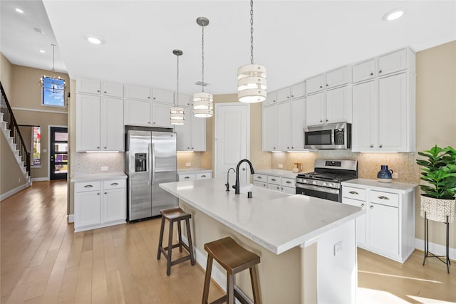21726 Grayson Highlands Way, Porter, TX 77365 - kitchen with appliances with stainless steel finishes, light countertops, a kitchen bar, decorative backsplash, and white cabinetry