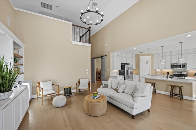 21726 Grayson Highlands Way, Porter, TX 77365 - living room featuring a high ceiling, a barn door, light wood-type flooring, a chandelier, and recessed lighting