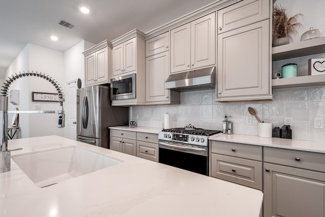 4327 Camden Springs Trl, Porter, TX 77365 - kitchen featuring appliances with stainless steel finishes, under cabinet range hood, gray cabinetry, decorative backsplash, and light countertops