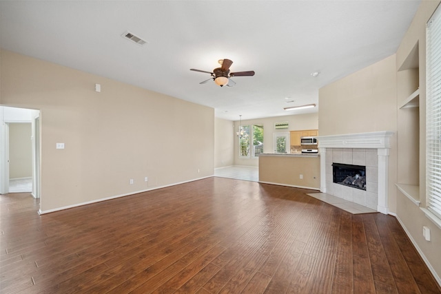 2207 Highland Hills Dr, Conroe, TX 77304 - unfurnished living room featuring ceiling fan, wood finished floors, and a tile fireplace