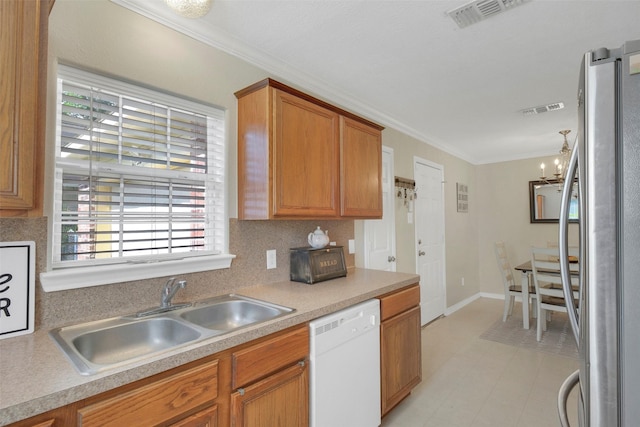 2222 3rd St, Rosenberg, TX 77471 - kitchen with freestanding refrigerator, white dishwasher, crown molding, light countertops, and brown cabinetry