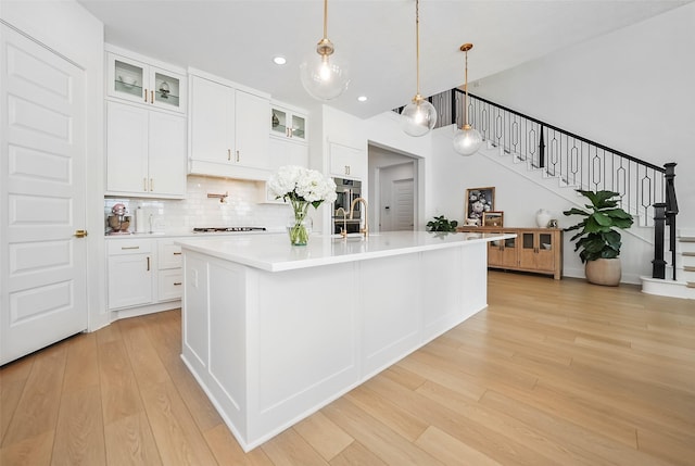 400 Horizon Light Ln, Katy, TX 77493 - kitchen featuring light wood-style floors, cooktop, light countertops, decorative backsplash, and white cabinetry