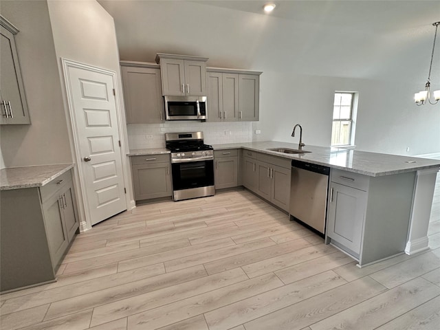 4301 Fenwick Rd, Texas City, TX 77591 - kitchen with stainless steel appliances, gray cabinets, light wood-type flooring, a peninsula, and tasteful backsplash