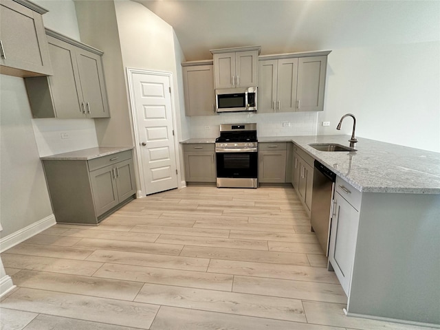 4301 Fenwick Rd, Texas City, TX 77591 - kitchen featuring stainless steel appliances, gray cabinetry, light wood-style flooring, light stone counters, and a peninsula