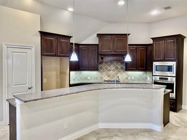 29018 Pinnacle Ridge Dr, Katy, TX 77494 - kitchen with appliances with stainless steel finishes, light stone countertops, tasteful backsplash, pendant lighting, and a center island with sink