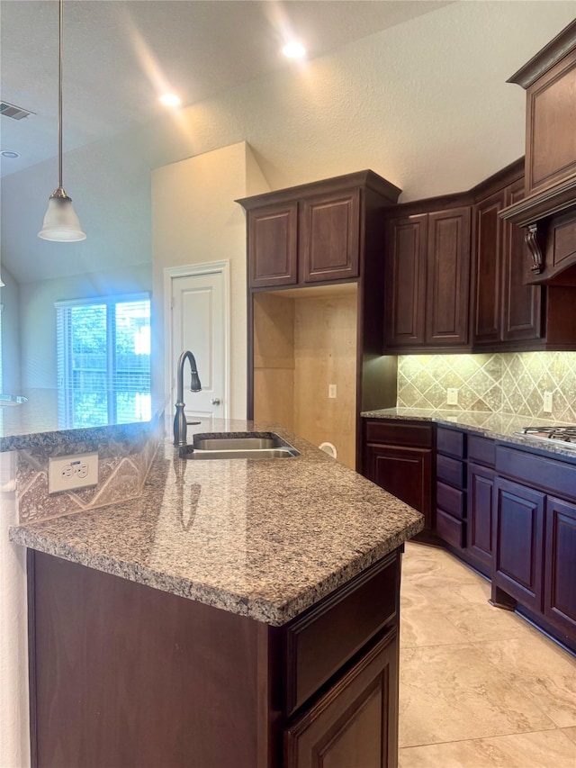 29018 Pinnacle Ridge Dr, Katy, TX 77494 - kitchen featuring decorative backsplash, stone countertops, stainless steel gas stovetop, decorative light fixtures, and a kitchen island with sink