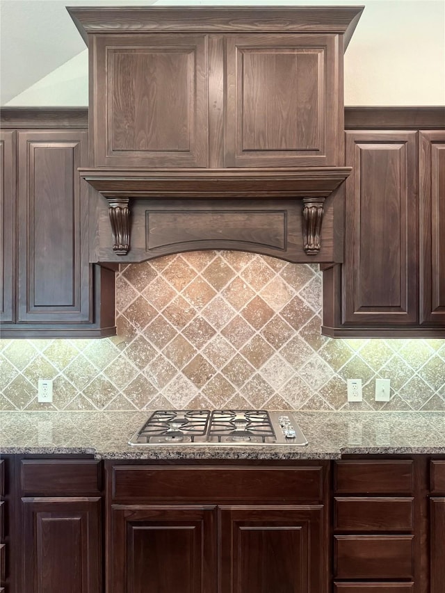 29018 Pinnacle Ridge Dr, Katy, TX 77494 - kitchen featuring stainless steel gas stovetop, dark brown cabinetry, light stone countertops, and backsplash