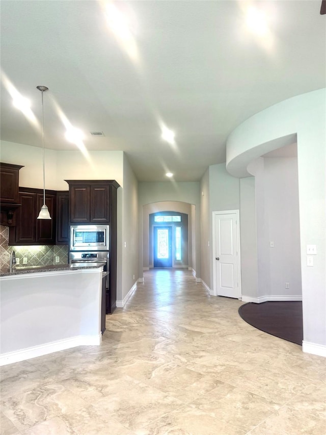 29018 Pinnacle Ridge Dr, Katy, TX 77494 - kitchen featuring stainless steel microwave, dark brown cabinetry, decorative backsplash, and decorative light fixtures