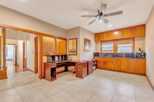 4316 Caduceus Pl, Galveston, TX 77550 - kitchen with brown cabinets, a ceiling fan, light tile patterned flooring, and dark countertops