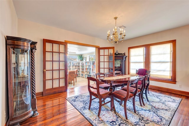 4316 Caduceus Pl, Galveston, TX 77550 - dining room featuring french doors, healthy amount of natural light, a chandelier, and wood finished floors