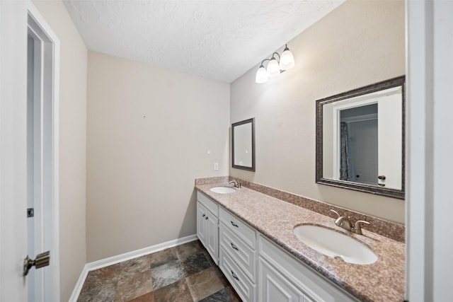 11607 Knobcrest Dr, Houston, TX 77070 - bathroom featuring double vanity, a textured ceiling, and stone finish floors