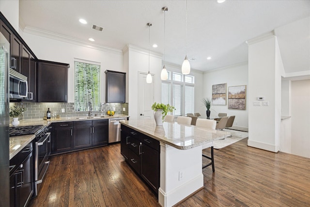 1124 W 24th St Unit B, Houston, TX 77008 - kitchen with appliances with stainless steel finishes, a breakfast bar area, a kitchen island, light stone counters, and decorative backsplash