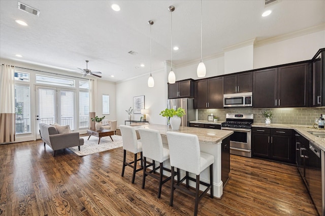 1124 W 24th St Unit B, Houston, TX 77008 - kitchen with stainless steel appliances, ornamental molding, open floor plan, a kitchen island, and a breakfast bar
