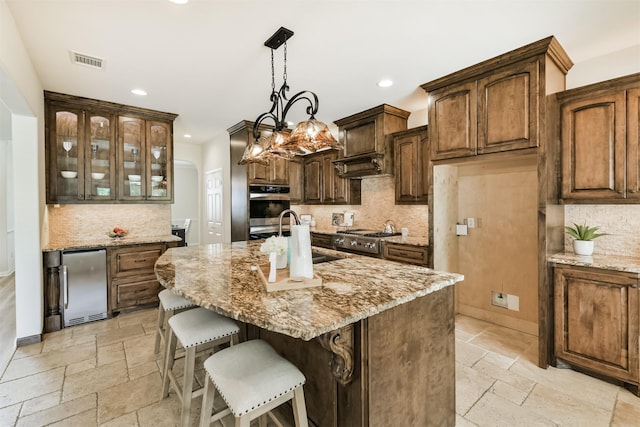 8006 Sports Haven Dr, Humble, TX 77346 - kitchen with stone tile flooring, appliances with stainless steel finishes, backsplash, recessed lighting, and light stone counters