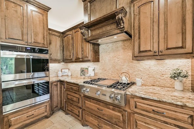 8006 Sports Haven Dr, Humble, TX 77346 - kitchen with appliances with stainless steel finishes, tasteful backsplash, light stone countertops, stone tile floors, and premium range hood