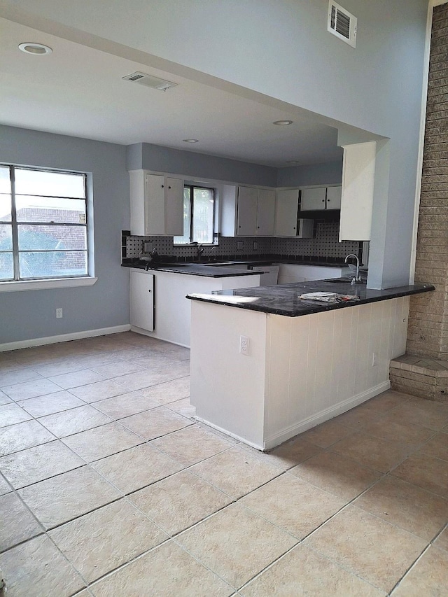 7807 Bellerive Dr, Houston, TX 77036 - kitchen with tasteful backsplash, dark countertops, a peninsula, light tile patterned floors, and white cabinets