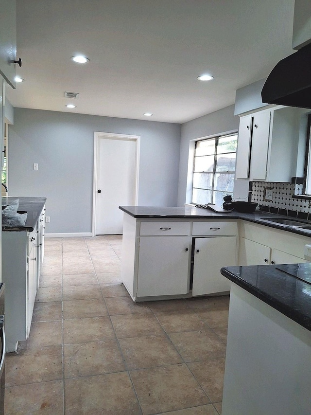 7807 Bellerive Dr, Houston, TX 77036 - kitchen featuring dark countertops, white cabinetry, a peninsula, recessed lighting, and decorative backsplash