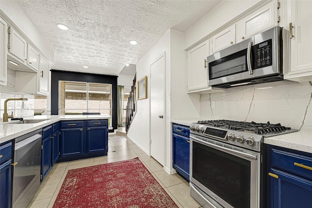 8727 Vinkins Rd, Houston, TX 77071 - kitchen with appliances with stainless steel finishes, blue cabinets, a textured ceiling, backsplash, and recessed lighting