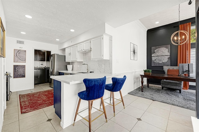 8727 Vinkins Rd, Houston, TX 77071 - kitchen with light countertops, a peninsula, freestanding refrigerator, recessed lighting, and a kitchen breakfast bar