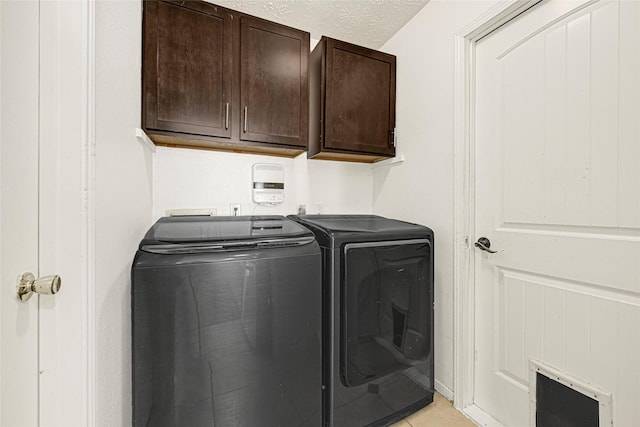 8727 Vinkins Rd, Houston, TX 77071 - laundry area with washing machine and dryer, cabinet space, light tile patterned floors, and a textured ceiling