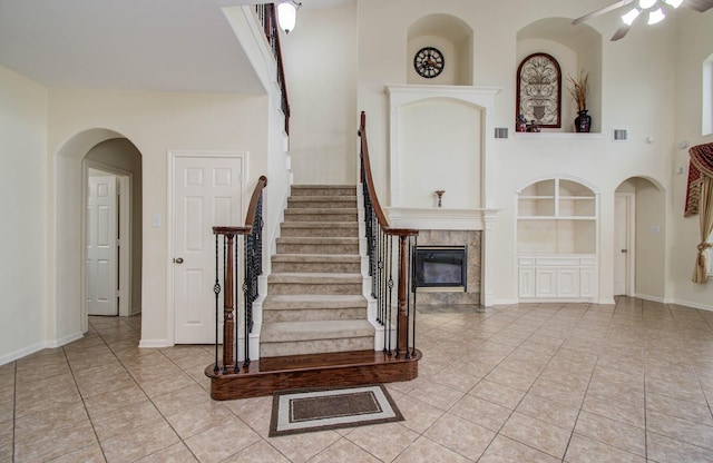 11704 Shoal Lndg, Pearland, TX 77584 - stairs featuring tile patterned flooring, built in shelves, a tiled fireplace, and ceiling fan