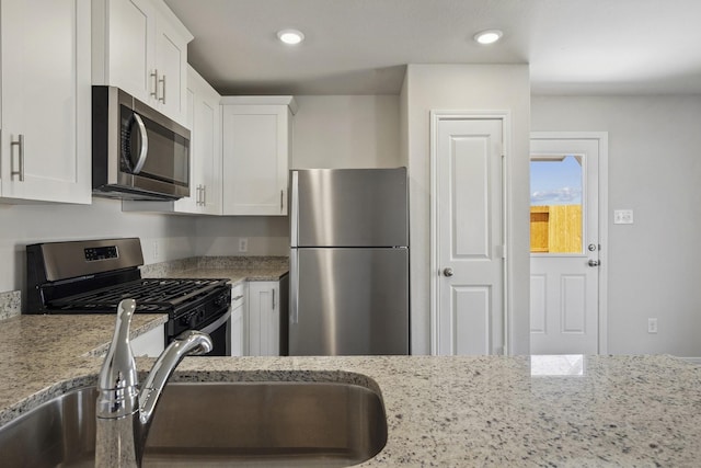 10430 Red Cardinal Dr, Cleveland, TX 77328 - kitchen featuring stainless steel appliances, white cabinets, light stone counters, and recessed lighting